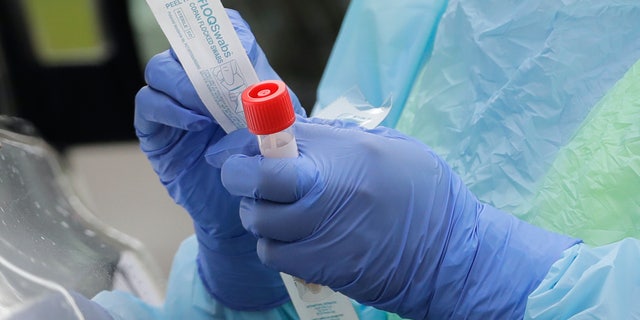 'Terrified' doctors risking their health fighting coronavirus dealt another blow -- pay cuts 3 In this April 2, 2020, file photo a nurse holds a vial and a swab at a drive-up coronavirus testing station at a hospital in Seattle. A federal report out Monday, April 6, finds that three out of four U.S. hospitals surveyed are already treating patients with confirmed or suspected COVID-19. (AP Photo/Ted S. Warren, File)