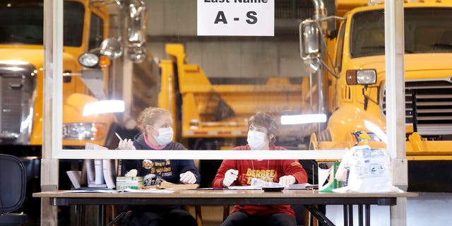 Sisters Kelly and Teal Rowe work behind a plexiglass barrier while waiting to verify voters at the town's highway garage facility, Tuesday, April 7, 2020, in Dunn, Wis. Voters in Wisconsin are casting ballots at polling places for the state's presidential primary election, ignoring a stay-at-home order over the coronavirus threat. (John Hart/Wisconsin State Journal via AP)