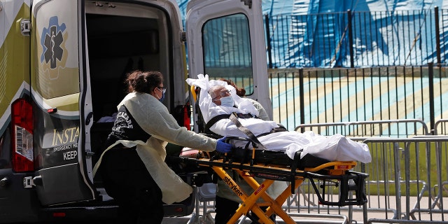 A patient is transferred from Elmhurst Hospital Center to a waiting ambulance during the current coronavirus outbreak, Tuesday, April 7, 2020, in New York. (AP Photo/Kathy Willens)