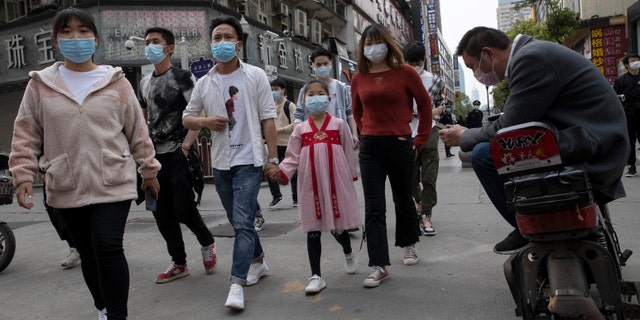 Residents walk along a retail street in Wuhan in central China's Hubei province on Wednesday, after a lockdown came to a close.