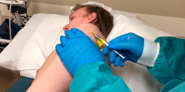 In this Wednesday, April 8, 2020 photo provided by the Center for Pharmaceutical Research, a participant in a COVID-19 coronavirus vaccine trial receives an injection in Kansas City, Mo. This early safety study, called a Phase 1 trial, is using a vaccine candidate developed by Inovio Pharmaceuticals.