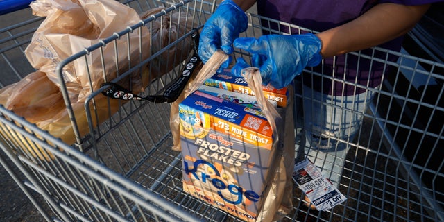 A gloved shopper prepares to load up her purchases in the Kroger parking lot in northeast Jackson, Miss., Wednesday, April 8, 2020. African Americans in Mississippi are being disproportionately affected by the new coronavirus, and many have underlying health problems that make them more vulnerable to it, the state epidemiologist said Tuesday. (AP Photo/Rogelio V. Solis)