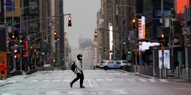 A man wearing a mask crosses a street in a quiet Times Square in New York City, April 9, 2020, during the coronavirus epidemic. (Associated Press)