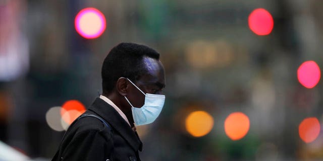 A man wearing a mask walks through New York's Times Square, Thursday, April 9, 2020, during the coronavirus epidemic. (AP Photo/Mark Lennihan)