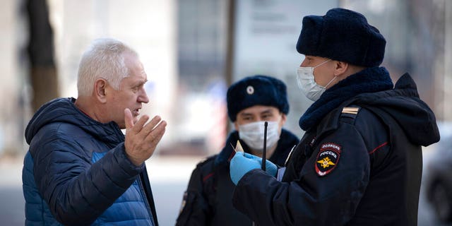 Russian police officers, wearing face masks to protect from coronavirus, check documents of a man to ensure a self-isolation regime due to coronavirus, in Moscow, Russia.