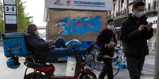 A delivery man wearing a mask against the coronavirus waits for orders in Wuhan in central China's Hubei province on Monday, April 13, 2020. 