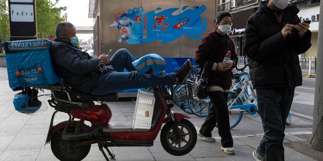 A delivery man wearing a mask against the coronavirus waits for orders in Wuhan in central China's Hubei province on Monday, April 13, 2020.