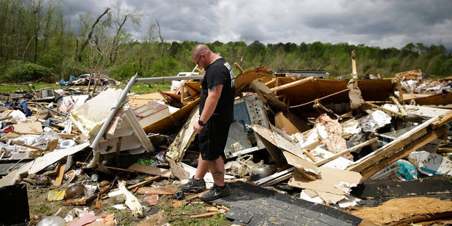 Aaron Pais kicking around debris at a mobile-home park wrecked by a tornado in Chatsworth, Georgia.