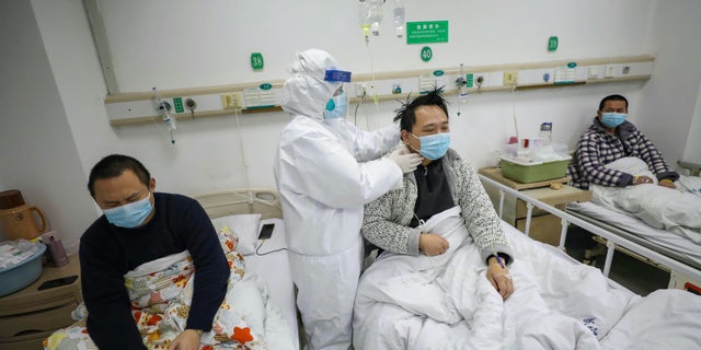 A doctor checks the conditions of a patient in Jinyintan Hospital, designated for critical COVID-19 patients, in Wuhan in central China's Hubei province. (Chinatopix Via AP)