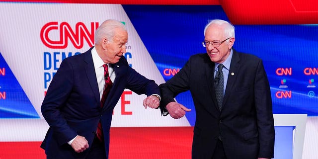 FILE - In this March 15, 2020, file photo, former Vice President Joe Biden, left, and Sen. Bernie Sanders, I-Vt., right, greet one another before they participate in a Democratic presidential primary debate at CNN Studios in Washington.  (AP Photo/Evan Vucci, File)