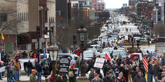 Flag-waving, honking protesters drove past the Michigan Capitol in Lansing on April 15 to show their displeasure with Gov. Gretchen Whitmer's orders to keep people at home and businesses locked during the new coronavirus COVID-19 outbreak. (AP Photo/Paul Sancya)