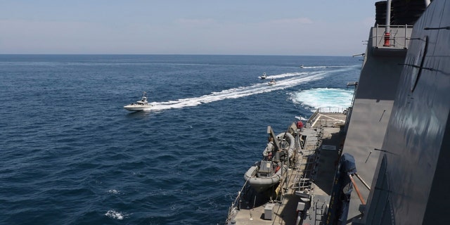 In this Wednesday, April 15, 2020, photo made available by U.S. Navy, Iranian Revolutionary Guard vessels sail close to U.S. military ships in the Persian Gulf near Kuwait. A group of 11 Iranian naval vessels made 