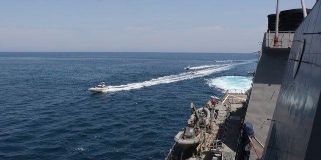 In this Wednesday, April 15, 2020, photo made available by U.S. Navy, Iranian Revolutionary Guard vessels sail close to U.S. military ships in the Persian Gulf near Kuwait. A group of 11 Iranian naval vessels made "dangerous and harassing" maneuvers near U.S. ships in the Persian Gulf near Kuwait on Wednesday, in one case passing within 10 yards (meters) of a U.S. Coast Guard cutter, U.S. officials said. Iranian officials did not immediately acknowledge the incident. (U.S. Navy via AP)