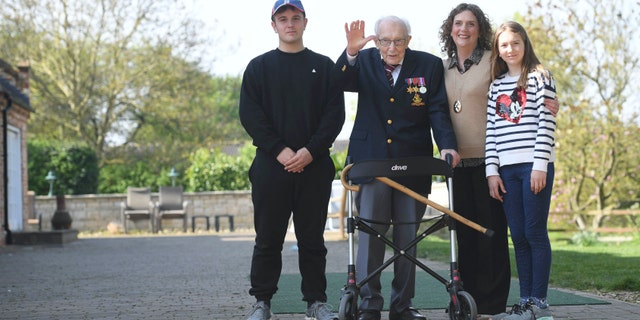 99-year-old war veteran Captain Tom Moore, with (left to right) grandson Benji, daughter Hannah Ingram-Moore and granddaughter Georgia, at his home in Marston Moretaine, Bedfordshire, after he achieved his goal of 100 laps of his garden - raising more than 12 million pounds for the NHS. Joe Giddens/PA Wire via AP