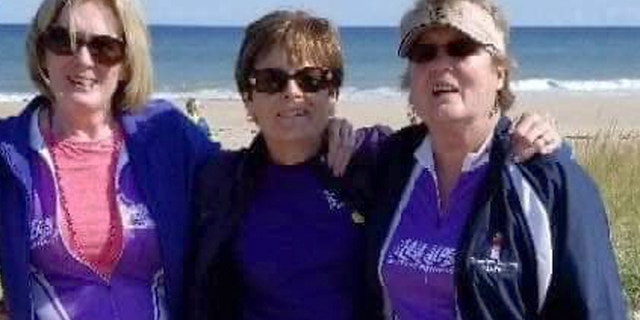 In this Sept. 2018 photo, Joanne Mellady, right, poses with her sisters Jean Sinofsky, left, and Joyce Smith, center, at a Massachusetts beach on Cape Cod during a bike trek fundraiser for Alpha 1.org. Mellady, who received a double lung transplant in 2007, died of the coronavirus in March 2020.