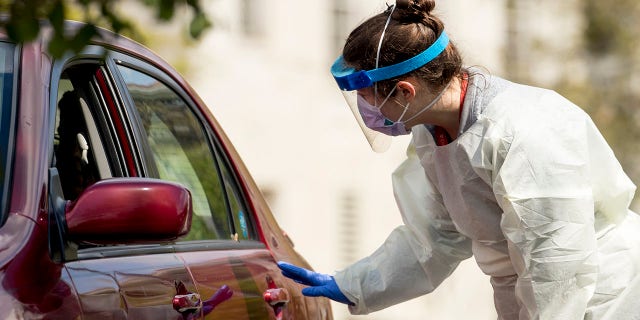 A medical worker asks a young man to roll down his window as for a COVID-19 test at a drive-through (drive-in) testing site at Trinity University last week in Washington. (AP Photo/Andrew Harnik)