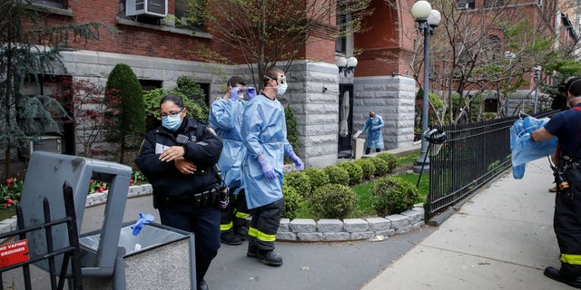 NYPD officers, FDNY firefighters, and emergency workers begin to discard and disrobe from their protective equipment after an emergency call at Cobble Hill Health Center Friday in the Brooklyn borough of New York. (AP Photo/John Minchillo)