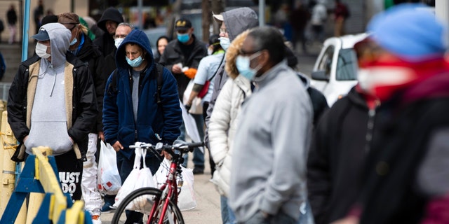 People wait in line to receive food during the coronavirus outbreak as part of a new initiative called Step Up to the Plate in the Kensington neighborhood of Philadelphia on April 17.  (AP Photo/Matt Rourke)