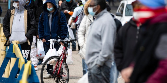 People wait in line to receive food during the coronavirus outbreak as part of a new initiative called Step Up to the Plate in the Kensington neighborhood of Philadelphia on April 17.  (AP Photo/Matt Rourke)