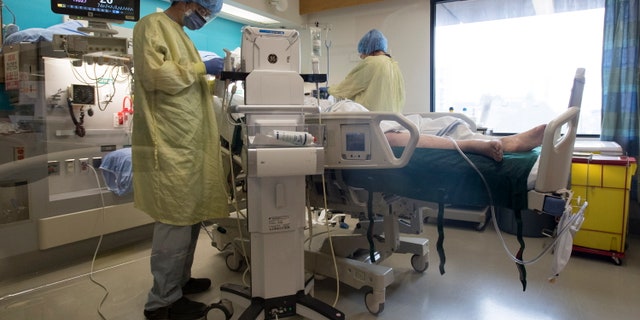 Resident doctor Kelvin Lou attends to a patient in a COVID suspect room in the COVID-19 intensive care unit at St. Paul's hospital in downtown Vancouver, British Columbia on April 21. <br data-cke-eol="1">
(Jonathan Hayward/The Canadian Press via AP)