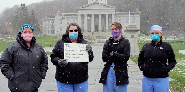 Nurses from Central Vermont Medical Center stand on the Statehouse lawn, Wednesday, April 22, 2020, in Montpelier, Vt., to counter a protest by a small group against Vermont's stay-at-home order. (AP Photo/Lisa Rathke)
