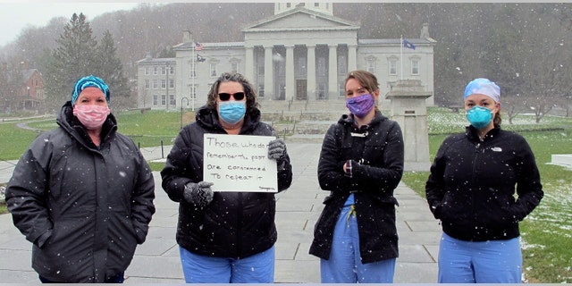 Nurses from Central Vermont Medical Center stand on the Statehouse lawn, Wednesday, April 22, 2020, in Montpelier, Vt., to counter a protest by a small group against Vermont's stay-at-home order. (AP Photo/Lisa Rathke)