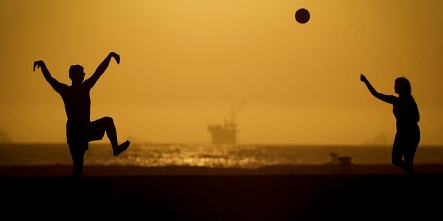 A couple plays volleyball on the sand Tuesday, April 21, 2020, in Huntington Beach, Calif. Warm temperatures are predicted for Southern California by the end of the week. (Associated Press)