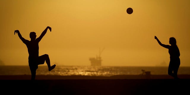 A couple plays volleyball on the sand Tuesday, April 21, 2020, in Huntington Beach, Calif. Warm temperatures are predicted for Southern California by the end of the week. (Associated Press)