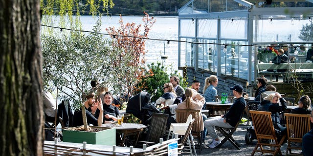 People drink and eat at an outdoor restaurant in Stockholm, Sweden, Sunday, April 26, 2020, amid the coronavirus pandemic.