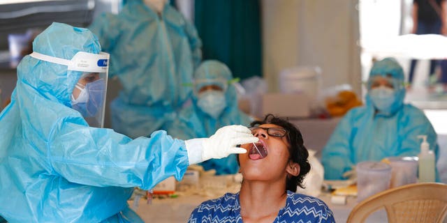 A health worker takes a swab test at a COVID-19 testing center in New Delhi, India, Monday, April 27, 2020. India’s main medical research organization has cancelled orders to procure rapid antibody test kits from two Chinese companies after quality issues and controversies over its price. 