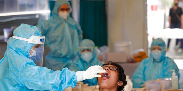 A health worker takes a swab test at a COVID-19 testing center in New Delhi, India, Monday, April 27, 2020. India’s main medical research organization has cancelled orders to procure rapid antibody test kits from two Chinese companies after quality issues and controversies over its price.