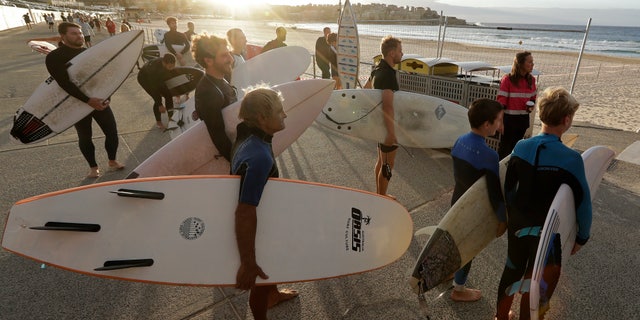 Surfers wait for officials to open Bondi Beach in Sydney, Tuesday, April 28, 2020, as coronavirus pandemic restrictions are eased. The beach is open to swimmers and surfers to exercise only. (AP Photo/Rick Rycroft)