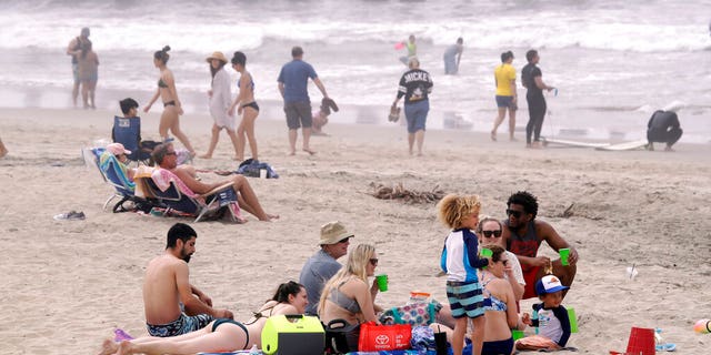 In this April 26, 2020, file photo, people sit on the beach in Huntington Beach, Calif. A memo sent to California police chiefs says Gov. Gavin Newsom will order all beaches and state parks closed starting Friday, May 1, to curb the spread of the coronavirus. The California Police Chiefs Association sent the bulletin to its members Wednesday evening. Association President Eric Nuñez said it was sent to give chiefs time to plan ahead of Newsom’s expected announcement Thursday.