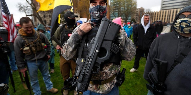 A protester carrying his rifle at the state Capitol in Lansing, Mich., Thursday. (AP Photo/Paul Sancya)