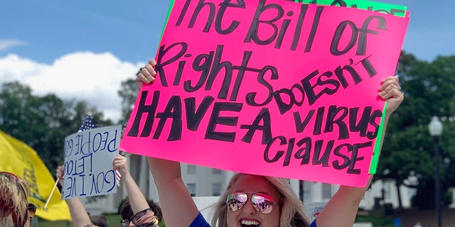 Kimmy Tillery, a hairdresser from Tuscaloosa, Ala., holds a sign during a protest to reopen Alabama's economy outside the Capitol in Montgomery, Ala., on Tuesday, April 21, 2020. (AP Photo/Kim Chandler)