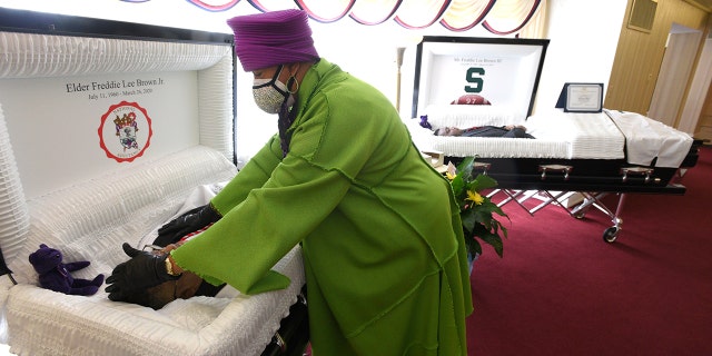 Sandy Brown touching the forehead of her late husband, Freddie Lee Brown, Jr., after she cried over her late son, Freddie Lee Brown, III, right, Friday in Flint, Mich. (Todd McInturf/Detroit News via AP)