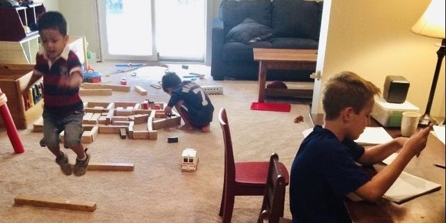 In the Batura family homeschooling room, Riley reads while his brothers Will and Alex work off some excess energy.