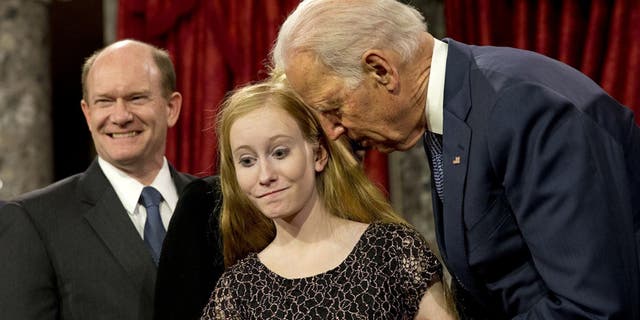 Then-Vice President Joe Biden leans in to say something to Maggie Coons, next to her father Sen. Chris Coons, D-Del., after Biden administered the Senate oath to Coons during a ceremonial re-enactment swearing-in ceremony, Jan. 6, 2015, in the Old Senate Chamber of Capitol Hill in Washington. (AP Photo/Jacquelyn Martin)