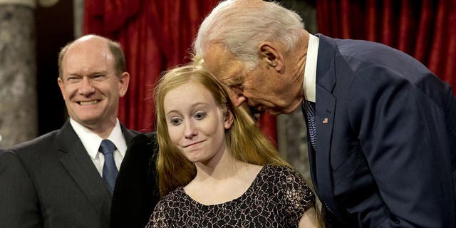 Then-Vice President Joe Biden leans in to say something to Maggie Coons, next to her father Sen. Chris Coons, D-Del., after Biden administered the Senate oath to Coons during a ceremonial re-enactment swearing-in ceremony, Jan. 6, 2015, in the Old Senate Chamber of Capitol Hill in Washington. (AP Photo/Jacquelyn Martin)