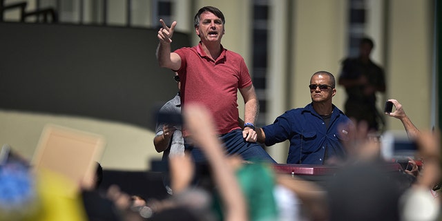 Brazil's President Jair Bolsonaro speaks to supporters during a protest in front the army's headquarters during the Army day, amid the new coronavirus pandemic, in Brasilia, Brazil, Sunday, April 19, 2020. Bolsonaro came out in support of a small protest Sunday that defended military intervention, infringing his own ministry's recommendations to maintain social distancing and prompting fierce critics. 