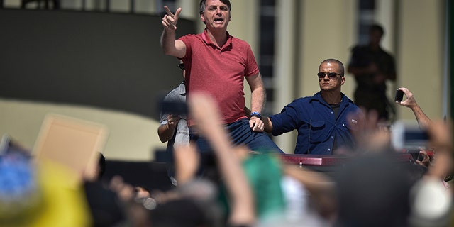 Brazil's President Jair Bolsonaro speaks to supporters during a protest in front the army's headquarters during the Army day, amid the new coronavirus pandemic, in Brasilia, Brazil, Sunday, April 19, 2020. Bolsonaro came out in support of a small protest Sunday that defended military intervention, infringing his own ministry's recommendations to maintain social distancing and prompting fierce critics.