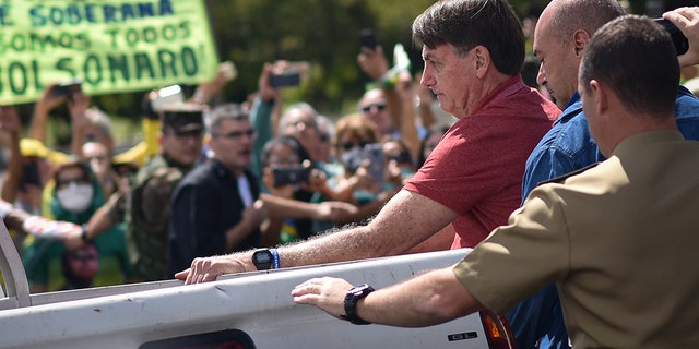 Brazil's President Jair Bolsonaro appears at a protest asking for military intervention in front the army's headquarters during the new coronavirus pandemic, in Brasilia, Brazil, Sunday, April 19, 2020.