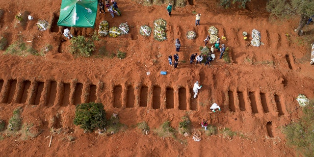 Cemetery workers in protective clothing bury a person who died of COVID-19, at the Vila Formosa cemetery in Sao Paulo, Brazil, Thursday, April 30, 2020. (AP Photo/Andre Penner)