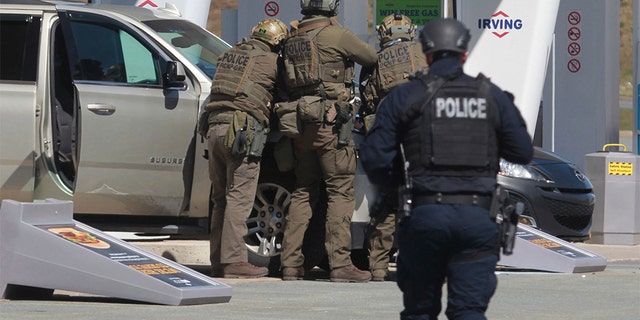 Royal Canadian Mounted Police officers prepare to take a suspect into custody at a gas station in Enfield, Nova Scotia. (Tim Krochak/The Canadian Press via AP)