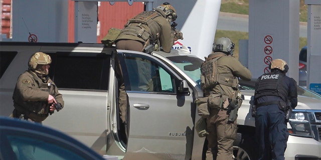 Royal Canadian Mounted Police officers prepare to take a suspect into custody at a gas station in Enfield, Nova Scotia on Sunday, April 19, 2020. (Tim Krochak/The Canadian Press via AP)