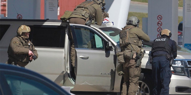 Royal Canadian Mounted Police officers prepare to take a suspect into custody at a gas station in Enfield, Nova Scotia on Sunday, April 19, 2020. (Tim Krochak/The Canadian Press via AP)