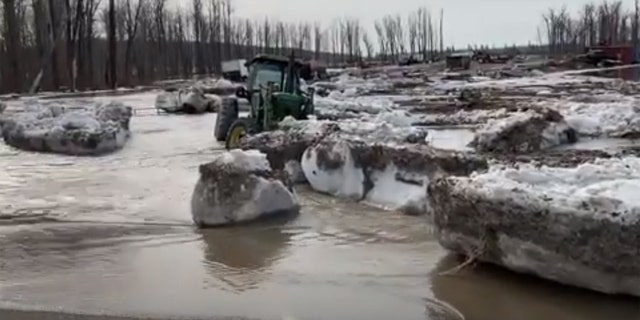 Chunks of ice and water can be seen flowing onto a street near Fort McMurray, Alberta after an ice jam caused major flooding in the region.