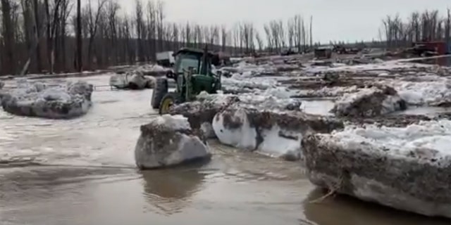 Chunks of ice and water can be seen flowing onto a street near Fort McMurray, Alberta after an ice jam caused major flooding in the region.