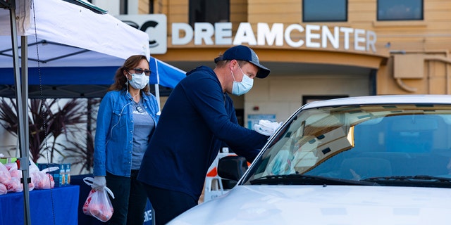 LA Dream Center co-founder Matthew Barnett hands out meals to a family.