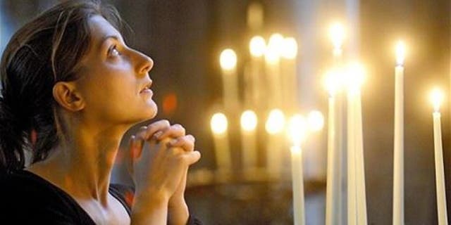 A woman is shown praying in church. We need to "bring the light of the gospel to a dark and evil world," said Dr. Kathy Koch of Fort Worth, Texas.